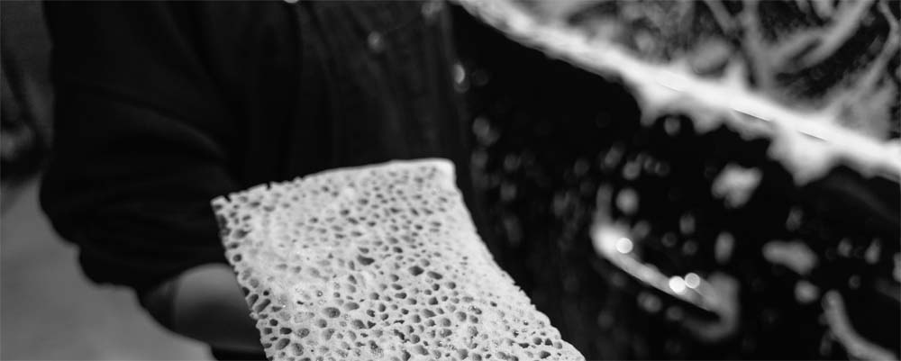 Person holding a sponge while washing a car